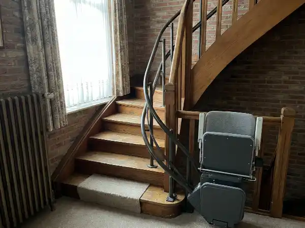 Gebogen rail van een traplift langs een trap met bordes